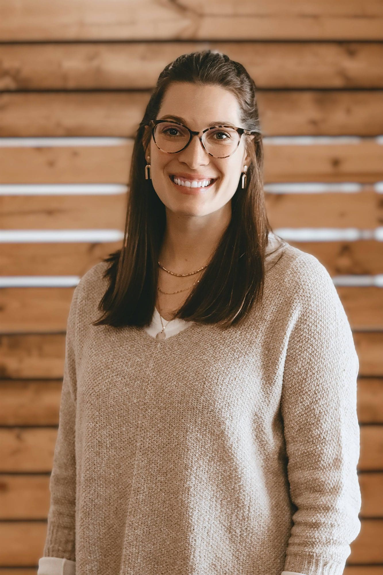 Dr. Kylee Johnson, smiling woman in a tan sweater with long brown hair and brown glasses
